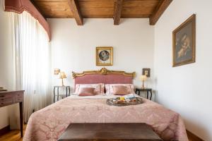 a bedroom with a large bed with a pink bedspread at Palazzo Benassi Penthouse nel cuore di Asolo in Asolo