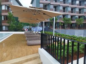 a patio with a tan umbrella and chairs and a pool at กิตติมา อพาร์ทเม้น in Nathon Bay