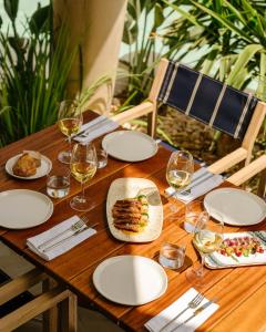 a wooden table with plates of food and glasses of wine at RIVELIAN Grand Menorca in Menorca