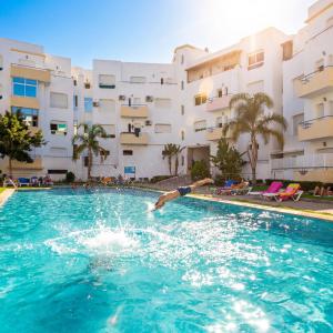 a man diving into a swimming pool in front of a building at Fantastique Appartement avec piscine sur la plage de Achakar de Tanger - proche du Cap Spartel & la Grotte d'Hercule de TANGER in Tangier