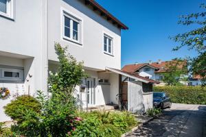 a white house with a car parked in the driveway at Charmantes Haus mit eigenem Garten in Prien am Chiemsee