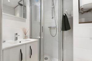a white bathroom with a shower and a sink at Petit cocon cosy en hyper centre in Villard-de-Lans