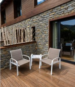 zwei Stühle auf einer Terrasse vor einem Gebäude in der Unterkunft XIA Hotel Boutique in Rialp