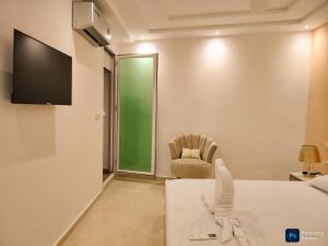a bedroom with a bed and a chair and a television at Fantastique Appartement avec piscine sur la plage de Achakar de Tanger - proche du Cap Spartel & la Grotte d'Hercule de TANGER in Tangier