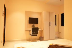 a bedroom with a chair and a tv on a wall at Shri Prasad Executive in Pandharpur