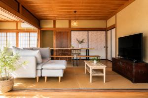 a living room with a couch and a tv at 貸切り200m2 林檎のワルツ 広い和モダン邸宅 星空とBBQ in Komoro