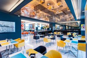 a dining room with tables and yellow chairs at AN Hotel Milano Melegnano in Carpiano