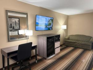 a hotel room with a desk and a television on the wall at Super 8 by Wyndham Harrison OH in Harrison