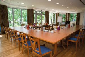 uma grande sala de conferências com uma grande mesa de madeira e cadeiras em Hotel Münnich em Münster