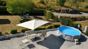 an umbrella and chairs next to a swimming pool at Private Pool River View Villa in Baião