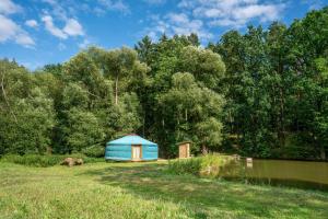 a blue tent in a field next to a pond at Jurta na Jitrech in Tábor +14 photos