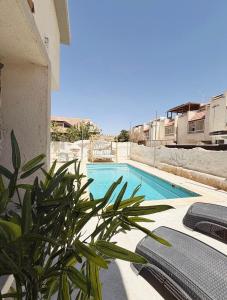 a pool with chairs and a plant next to a building at Villa Sea House in Eilat