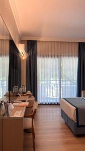 a hotel room with a bed and a desk and a bed and windows at Pam Thermal Hotel Clinic & Spa in Pamukkale +41 photos