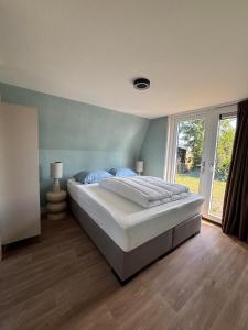 a bedroom with a large bed and a large window at Lodge Wieringen in Hippolytushoef