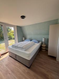 a large bed in a room with a window at Lodge Wieringen in Hippolytushoef