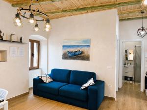 a blue couch in a living room with a painting of a boat at Ana & Angelo Stone House Vuno Himarë in Vuno