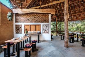 a dining room with tables and a brick wall at Manthally Cabanas in Hikkaduwa