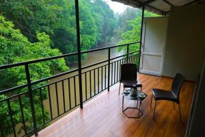 a balcony with two chairs and a view of a river at kumba stay in Kumbakonam