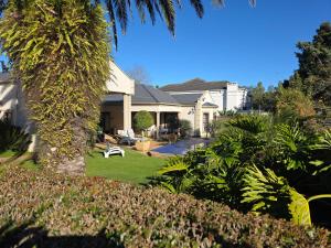 a house with a palm tree in the yard at Plovers Rest in George