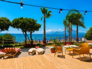 a patio with chairs and palm trees and the ocean at Beach Hotel Terracotta in Sapri