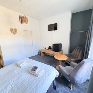 a bedroom with a bed and a chair and a tv at The Sandpiper in Barmouth