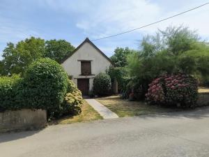 a small white house with some bushes and flowers at La Petite Grange in Langourla