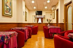 une salle d'attente avec des chaises rouges et une télévision à écran plat dans l'établissement Hotel Brignole, à Gênes