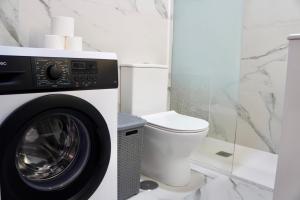 a bathroom with a washing machine and a toilet at Seguro Spacious apartment with roomy terrace, newly renovated in Puerto de Santiago +14 photos