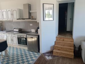 a kitchen with white cabinets and a wooden floor at le bégare  +7 photos