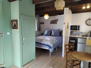 a bedroom with a bed and a table and a kitchen at La Petite Grange in Langourla