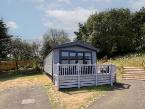 a small blue shed with a white fence at The Pines 3 Bedrooms in Northwich