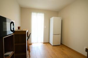 a room with a refrigerator and a desk with a television at T2 Les Suites du Roubion in Montélimar +2 photos