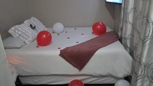 a bed with red and white balloons on it at BluSash in Durban