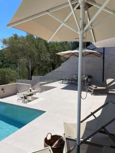 a patio with an umbrella next to a swimming pool at Nomade Villas in Agios Ioannis Peristerion