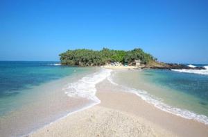 a beach with a small island in the ocean at Nisho House Hiriketiya in Hiriketiya