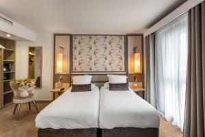 a hotel room with two beds and a window at Hotel America in Cannes