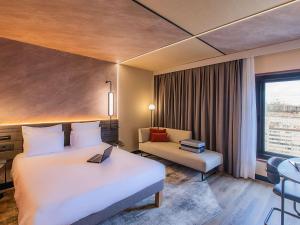 a hotel room with a bed and a couch and a window at Novotel Lisboa in Lisbon