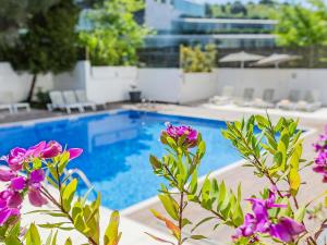 a swimming pool with purple flowers in the foreground at Novotel Lisboa in Lisbon