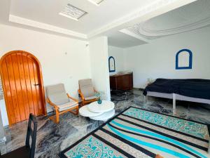 a bedroom with a bed and two chairs and a rug at Dar Mimouna Djerba in Tianest +39 photos