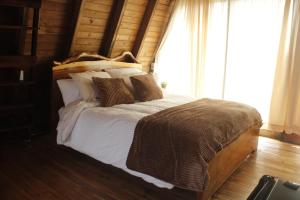 a bedroom with a large bed with white sheets and pillows at Mount House Lodge in Guano