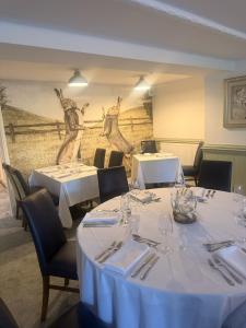 a dining room with white tables and chairs and a mural at The Blue Bell Inn in Weaverthorpe