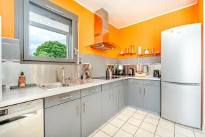 a kitchen with orange walls and a white refrigerator at La Maison de Rolie in Plévin