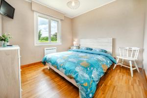 a bedroom with a bed and a chair and a window at La Maison de Rolie in Plévin