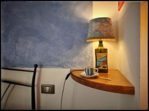 a table with a lamp and a cup and a bottle at Pietra Di Mare in Biassa