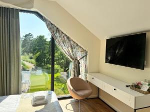 a bedroom with a large window with a tv and a chair at Szum Rzeki - Noclegi nad Brdą - Bory Tucholskie in Nadolna Karczma