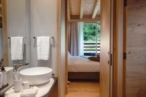 a bathroom with a white sink and a bedroom at LVG Hotel Collection - Cascata d'Otro Mountain Lodge in Alagna Valsesia +51 photos