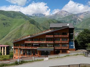 a large building with mountains in the background at Lens Design Hotel in Kazbegi