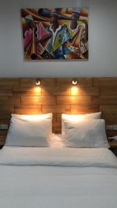 a bed with two pillows and a painting above it at Afrilodge Liberia in Monrovia +29 photos