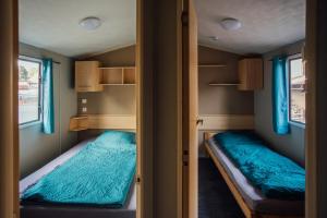 two beds in a small room with blue curtains at Tiny House Kleinrettbach 