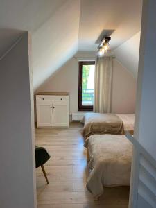 a attic room with two beds and a window at Domowe Zacisze in Augustów
